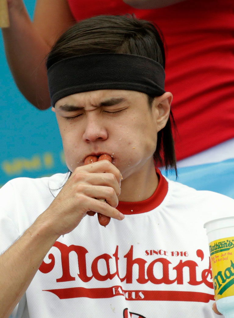 Matt Stonie, dando cuenta de uno de los 62 perritos calientes que comió para ganar el Nathan’s Famous Fourth of JulyHot-Dog Eating Contest en Coney Island, Nueva York. Fuente: The Seattle Times, 4 de julio de 2015. PETER FOLEY/EPA.